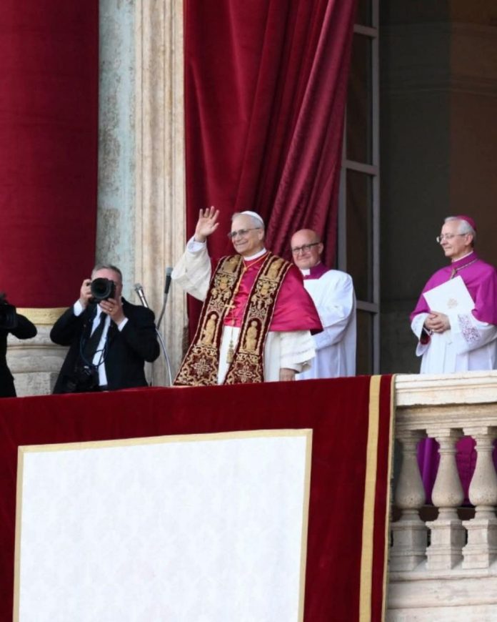 Paus Leo XIV menyapa umat dari balkon Basilika Santo Petrus pada 8 Mei 2025 setelah terpilih sebagai pontifex Amerika pertama, ditemani kardinal dan fotografer.