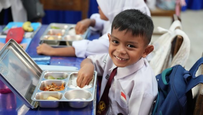 Ilustrasi seorang siswa SD menyantap paket Program Makan Bergizi Gratis (MBG).