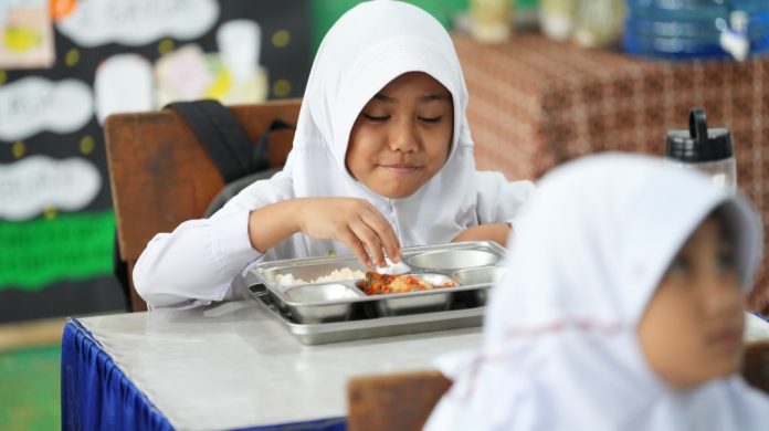 Seorang siswi menyantap paket Program Makan Bergizi Gratis (MBG).